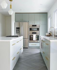 a modern kitchen with stainless steel appliances and herringbone tile flooring, along with white cabinets