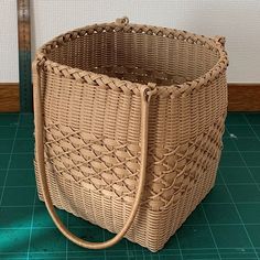 a brown wicker basket sitting on top of a green tile floor