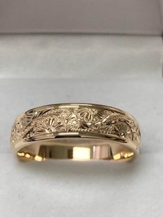 a yellow gold wedding band with flowers on the side and leaves inlaying it