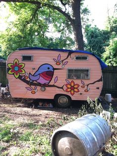 a pink trailer with a bird painted on it's side next to a tree