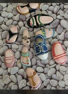 several pairs of painted wooden shoes sitting on top of a pile of rocks next to each other