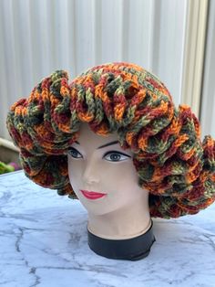 a mannequin head wearing a crocheted hat on top of a table