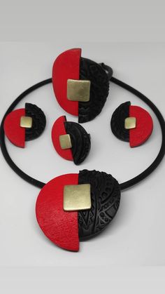 three pieces of red and black jewelry on a white surface