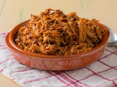 a bowl filled with shredded meat sitting on top of a table