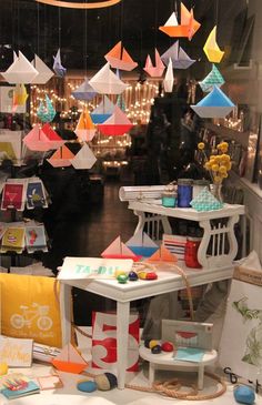 there are many colorful kites hanging from the ceiling in this shop front window display