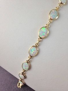 "Beautiful bracelet of Gilson Opals! This delicate bracelet is stunning with Opal gemstones. These are Gilson Opals which are man made but retain all of the attributes and composition of earth-mined Opals without the high cost. The Opals are bezel set in 24k gold over Sterling silver. The backs are open to allow the light to shine through and refract the amazing dance of colors in each Opal stone! The Opal links are accented with a lovely flat gold overlay chain that adds to the luxurious feel o Oval Opal Bracelets As Gift, Oval Opal Bracelets For Gifts, Modern Formal Opal Jewelry, Elegant Hypoallergenic Opal Jewelry, White Modern Jewelry With Simple Design, White Modern Jewelry Simple Design, Modern White Jewelry With Simple Design, Modern Simple White Jewelry, Opal Gemstone Bracelet Jewelry