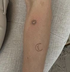 a woman's arm with a small sun and moon tattoo on the left forearm