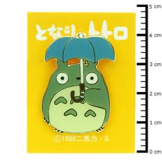 a green and white totoro with an umbrella on it's lapel