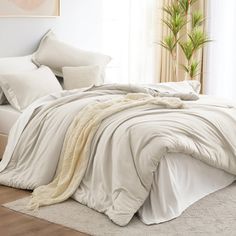 an unmade bed with white sheets and pillows