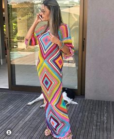 a woman in a colorful dress talking on her cell phone while standing on a deck