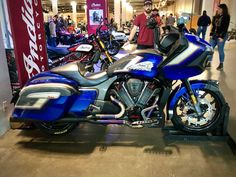 a blue motorcycle is parked in the middle of a showroom with people looking at it