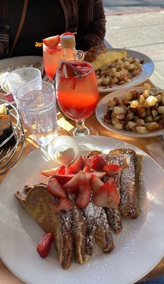 a plate with french toast, strawberries and other food on it sitting on a table