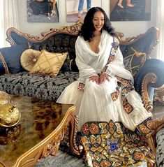 a woman sitting on top of a couch next to a table