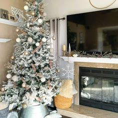 a decorated christmas tree in front of a fireplace with a flat screen tv above it