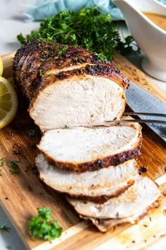 sliced pork on a cutting board with lemons and parsley