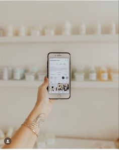 a person holding up a cell phone in front of shelves