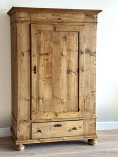 an old wooden armoire sitting on top of a hard wood floor next to a wall