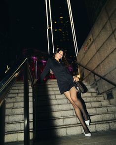 a woman in tights and heels walking up some stairs at night with her hand on her purse