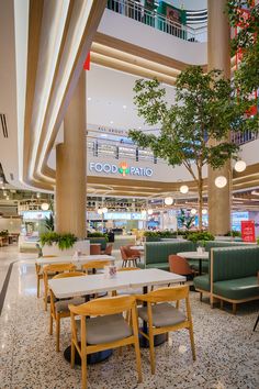 the inside of a restaurant with tables, chairs and plants on the floor in front of it