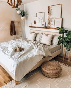 a bed with white sheets and pillows in a bedroom next to a potted plant