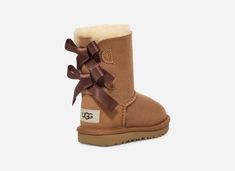 Your little one will adore these UGG® Toddlers' Bailey Bow II Boots with sweet silky bows in classic Brown. Designed for comfort and style, these boots feature a super-soft sheepskin lining and ultra-lightweight outsole for traction and durabilityâ€”perfect for active kiddos.The outsole of this product is either a SugarSole outsole, which is a responsible compound using sugarcane foam that allows us to reduce dependency on fossil fuels by replacing petroleum-based ethylene, or a Treadlite by UGG Toddler Uggs, Ugg Boots With Bows, Toddler Ugg Boots, Ugh Boots, Kids Ugg Boots, Baby Uggs, Bow Boots, Bailey Bow, Fossil Fuels