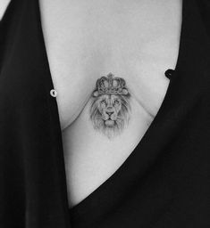 a woman's chest with a tattoo of a lion wearing a crown on it