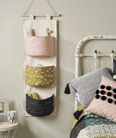 a bed with two pillows hanging on the wall next to a white metal headboard