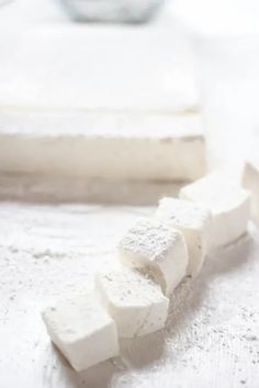 several pieces of marshmallow sitting on top of a white countertop next to a glass bowl