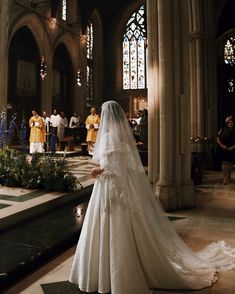 a woman in a wedding dress is standing at the alter with other people around her