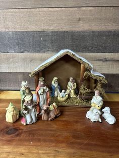 a nativity scene with figurines in front of it on a wooden table