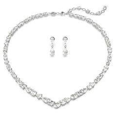 Exquisite refinement is brought to life in this show-stopping jewelry set from the Mesmera family. The necklace is made with a string of eye-catching Swarovski Zirconia on a rhodium plating setting, all produced in a surprising mix of cuts and sizes. For extra luxury, the elongation is completed with a lobster closure and a scattering of Swarovski Zirconia. The light-catching earrings are also rhodium plated, with a bold hanging design featuring luminous pear-cut crystals. Gift this set to a lov Swarovski Earrings Crystals, Swarovski Jewelry Set, Swarovski Necklace Crystal, Swarovski Jewelry Aesthetic, White Gold Jewelry Set, Swarovski Jewelry Necklace, Bride Jewelry Set, Necklace Luxury, Expensive Jewelry Luxury