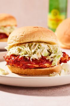 a close up of a sandwich on a plate with coleslaw in the background