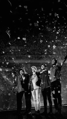 a group of people standing on top of a stage with confetti in the air