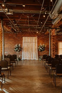 an empty room with rows of chairs and string lights hanging from the ceiling, decorated with flowers