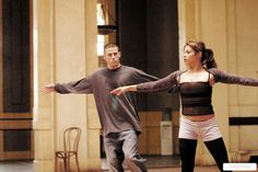 a man and woman are dancing together in an indoor dance studio with their arms stretched out