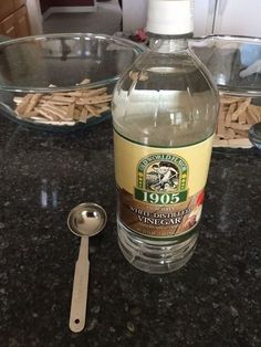 a bottle of vinegar sitting on top of a counter next to a bowl of noodles