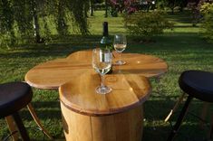 two wine glasses sitting on top of a wooden barrel next to stools and table