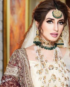 a woman in a bridal outfit with jewelry on her neck and headpieces