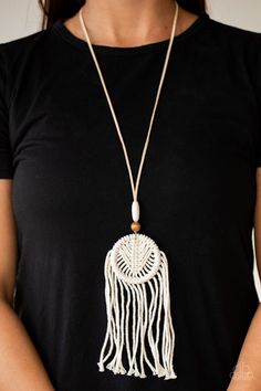 a woman wearing a black t - shirt and a white necklace with a green bead