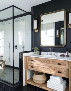 a bathroom with black walls and white tile flooring, two mirrors on the wall