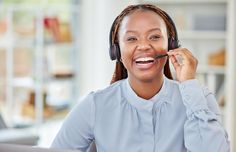 a woman with headphones on talking on her cell phone while sitting in front of a laptop