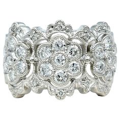 a white gold ring with diamonds on the sides and an intricate flower design in the middle