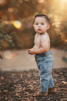 a little boy that is standing up in the dirt with his hands on his hips