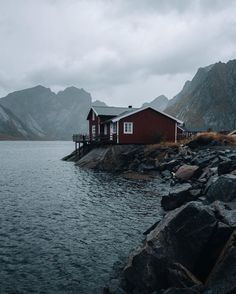 a red house sitting on top of a rocky shore