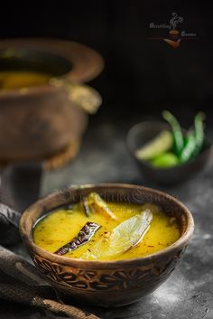 a brown bowl filled with soup and garnished with lemon wedges on the side