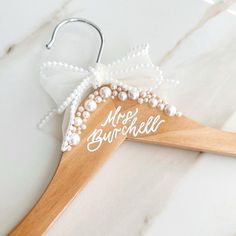 a wooden hanger with a personalized name and pearls hanging from it's side