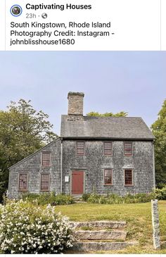 an old gray house with red doors and windows on the front, surrounded by greenery