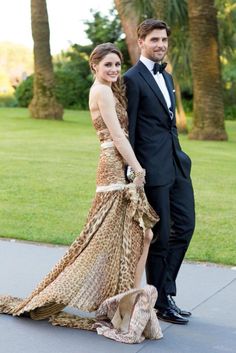 a man in a tuxedo and a woman in a leopard print dress pose for the camera