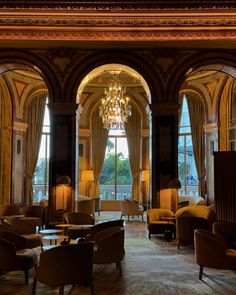 an elegant hotel lobby with chandelier and seating area in front of large windows