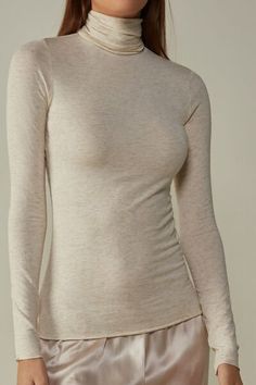 Long sleeve high collar top in soft modal ultralight with cashmere and lamé thread. Elegant Soft Texture Winter Tops, Fitted Tops For Layering With Soft Texture, Elegant Winter Tops With Thumbholes, Elegant Beige Top For Loungewear, Seamless Turtleneck Top For Layering, Elegant Loungewear Tops For Winter, Soft Texture Fitted Tops For Fall, Elegant Winter Tops For Loungewear, Elegant Winter Loungewear Tops